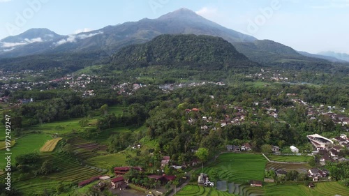 Aerial view of Mount Welirang with terraced rice fields, rural village settlement, and green valley landscape in East Java, Indonesia