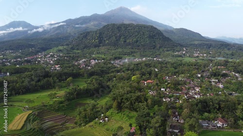 Aerial view of Mount Welirang with terraced rice fields, rural village settlement, and green valley landscape in East Java, Indonesia
