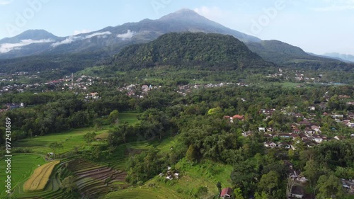 Aerial view of Mount Welirang with terraced rice fields, rural village settlement, and green valley landscape in East Java, Indonesia