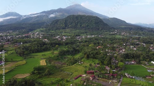 Aerial view of Mount Welirang with terraced rice fields, rural village settlement, and green valley landscape in East Java, Indonesia
