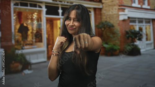 Canvas-taulu Woman with fists raised in a playful boxing pose on street storefront; confidence resilience determination courage