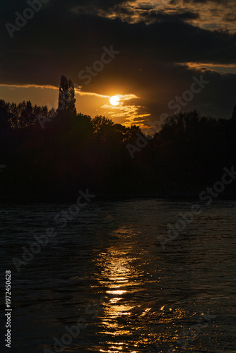 Sunset behind a forest on the riverbank.