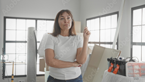 Wallpaper Mural Woman points finger forward in building filled with moving boxes and tools; home planning determination. Torontodigital.ca