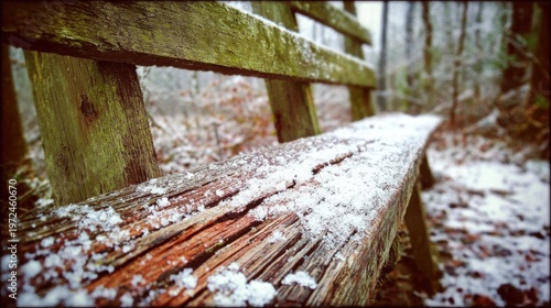 A cracked and weathered wooden bench covered in fresh snow sits outdoors in a tranquil winter park setting.