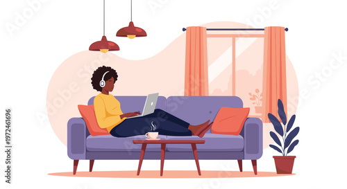 Black woman wearing headphones relaxes on a purple sofa while working on her laptop and enjoying coffee at home.