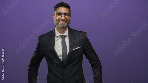 Canvastavla Business man hispanic in a dark suit with glasses and tie smiling with hands on hips in purple studio; confident success