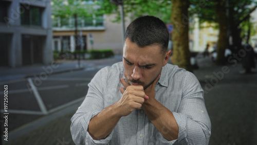 Fotografie Young hispanic man with furrowed brow and closed eyes clutching throat on urban street corner; distress