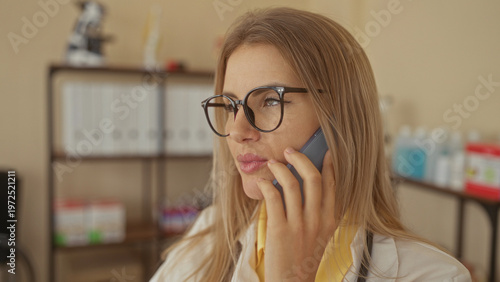 Cuadro en lienzo Woman doctor holding phone to ear with hand on cheek, glasses and stethoscope visible in clinic building; concerned care