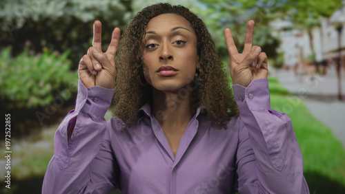 Obraz na plátne Woman lifts both hands in airquotes gesture with visible fingers in green park; sarcasm irony humor satire