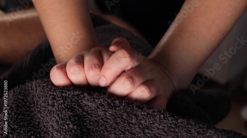 Close up of therapist kneading male thigh muscle with fists on massage table