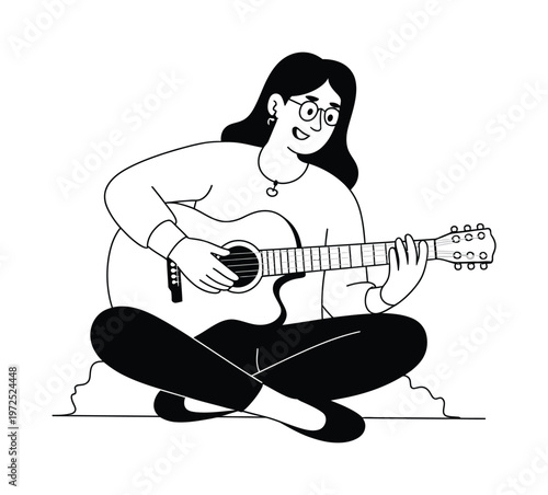 A woman with glasses playing an acoustic guitar, sitting cross-legged