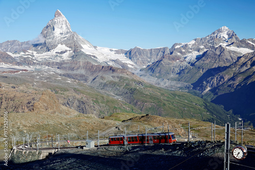 Wallpaper Mural A tourist train travels on the cogwheel railway near Gornergrat Station on a beautiful summer day with the pyramidal Matterhorn peak under blue clear sky in background, in Zermatt, Valais, Switzerland Torontodigital.ca