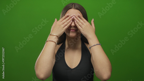Foto Caucasian teenage girl claps hands with open mouth in front of bright green screen in studio; surprise