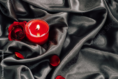 Bilde på lerret Red candle and rose on dark satin fabric create an intimate setting for a specia