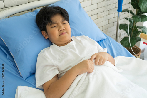 Sick asian boy lying on hospital bed. Healthcare and medical concept.