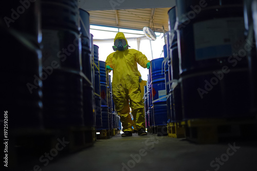 Obraz na plátně Hazmat worker walking between chemical barrels in industrial warehouse, toxic sa