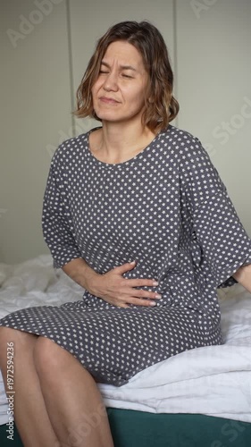 Blonde Woman 40+ Suffering from Abdominal Pain on Bed in Bedroom