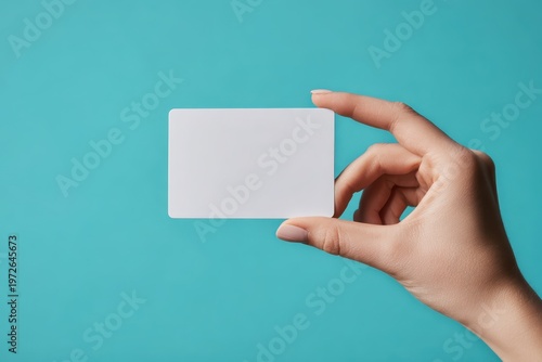 Female hand holding blank paper business card. Person showing blank credit business gift membership card isolated on solid blue background. Closeup voucher template, mock-up. Empty name slip Flat lay