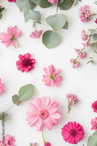 Fresh pink flowers and eucalyptus leaves arranged on a white surface vertical frame