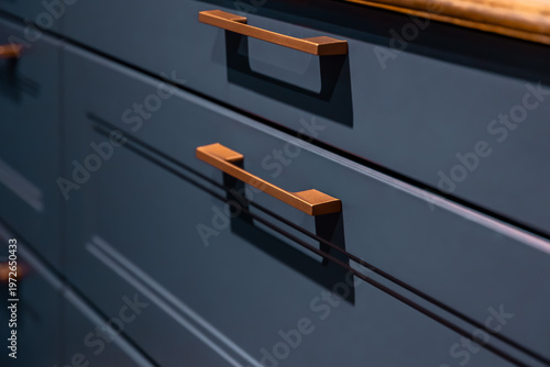 Modern copper handles on blue kitchen drawers. Stylish furniture hardware in minimalist style.