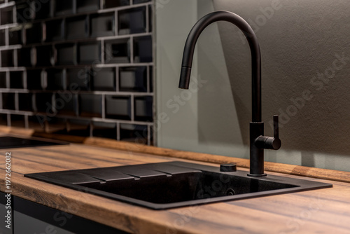 Modern kitchen sink with black faucet and wooden countertop. Stylish minimal kitchen interior design