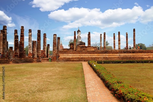 Canvas Print View of a Buddha statue seated among decadent columns of a ruined shrine in Wat