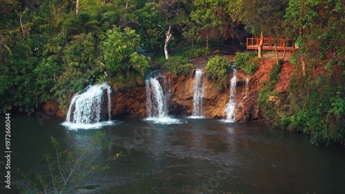 Sai Yok Yai waterfall in Thailand flowing into river surrounded by lush tropical jungle in national park, Wide scenic cascade and natural beauty, travel and tranquility slow motion 4k