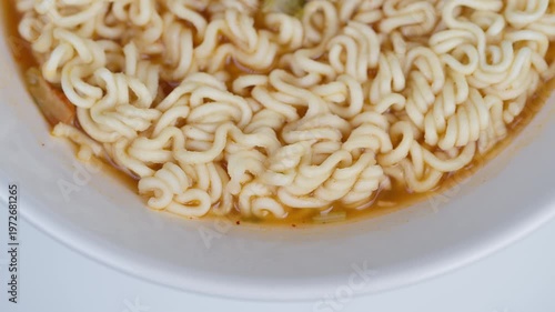 Steaming noodle bowl. Delicious warm instant noodles. Closeup of freshly cooked curly noodles in broth. White bowl filled with steaming flexible noodles in light broth