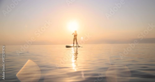 Young woman walking on sup board by the sea during summer vacation