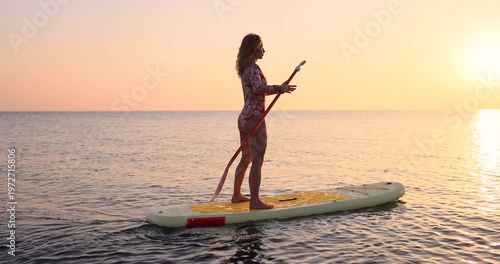 Young woman walking on sup board by the sea during summer vacation. Slow motion