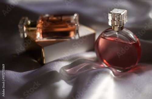 Two luxury women’s perfume bottles on silk fabric, elegant fragrance and beauty concept