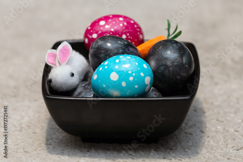 Easter decoration with colorful painted eggs and cute bunny toy in a bowl