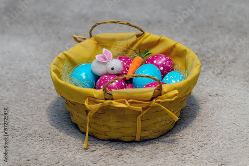 Easter decoration with colorful painted eggs and cute bunny toy in a bowl