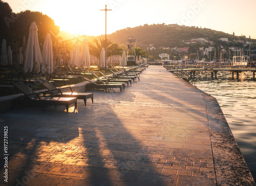 Seaside promenade with loungers in Portorož at sunrise
