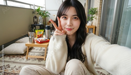 休日のバルコニーでスナックを前にピースサインをする女性