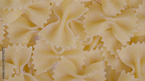 Uncooked pasta display. Pale golden uncooked pasta with serrated edges detailed closeup. Studio shot of bowshaped uncooked pasta showcasing textured surface and intricate edges