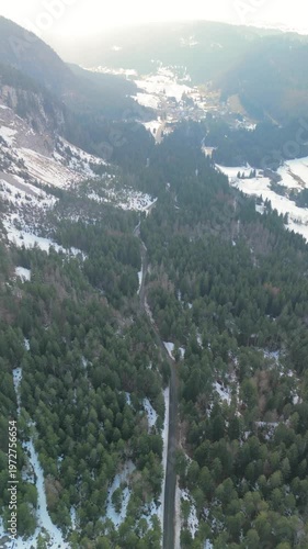 Drone flying over a road in the Jura mountains winter forest