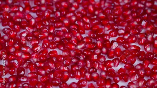 Studio illumination accentuates shiny pomegranate seeds and detailed textures. Expert lighting showcases glossy surface and intricate structure of pomegranate arils in high detail