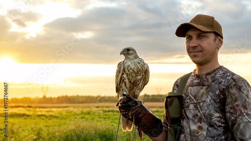 Man holds falcon at golden sunset