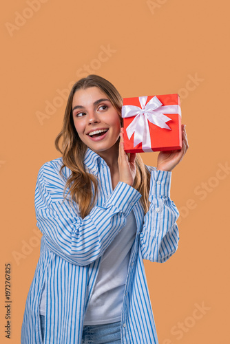 Happy Grateful Woman With Gift Box On Beige Wall. Lady Smiling,Present, Surprise