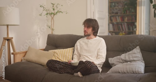 A person savors their meal on the couch, embracing comfort and warmth in a welcoming living space filled with joy