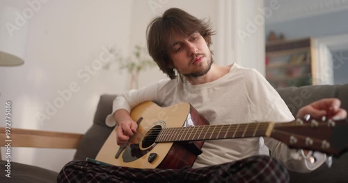 A talented guitarist embraces the peaceful moment, creating soothing music in a cozy living room filled with light