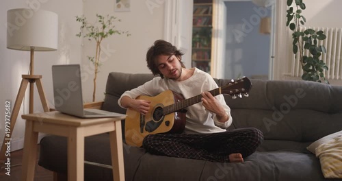 Enjoy a relaxing atmosphere as a young man plays soothing melodies on his guitar, creating a tranquil home experience