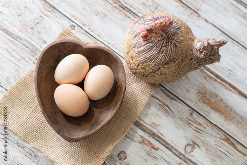 Fresh Brown Eggs in Wooden Bowl with Hen on Rustic White Wood Overhead View