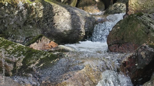Mossy Stream Flowing Through Rocky Terrain.