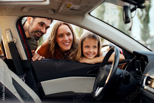 Foto Happy family smiling while looking inside car through open window, choosing new