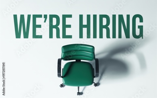 A green office chair sits empty under a sign that reads we're hiring in an office.