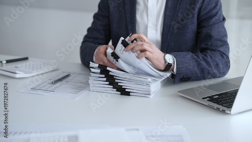 Konstfotografi Business professional organizing documents at desk, managing paperwork and financial reports, working on taxes or corporate accounts with a laptop and calculator for audit preparation