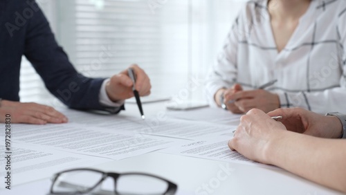 Fotografie Business people discussing contract documents on a white desk, analyzing clauses