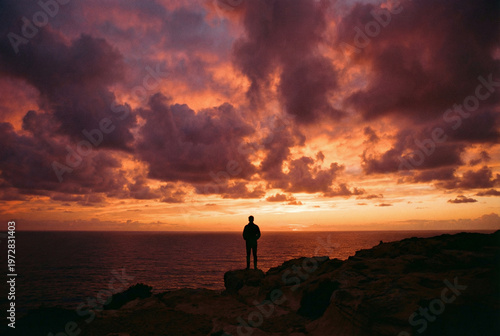 Silhouette of a person looking at the sunset over the ocean